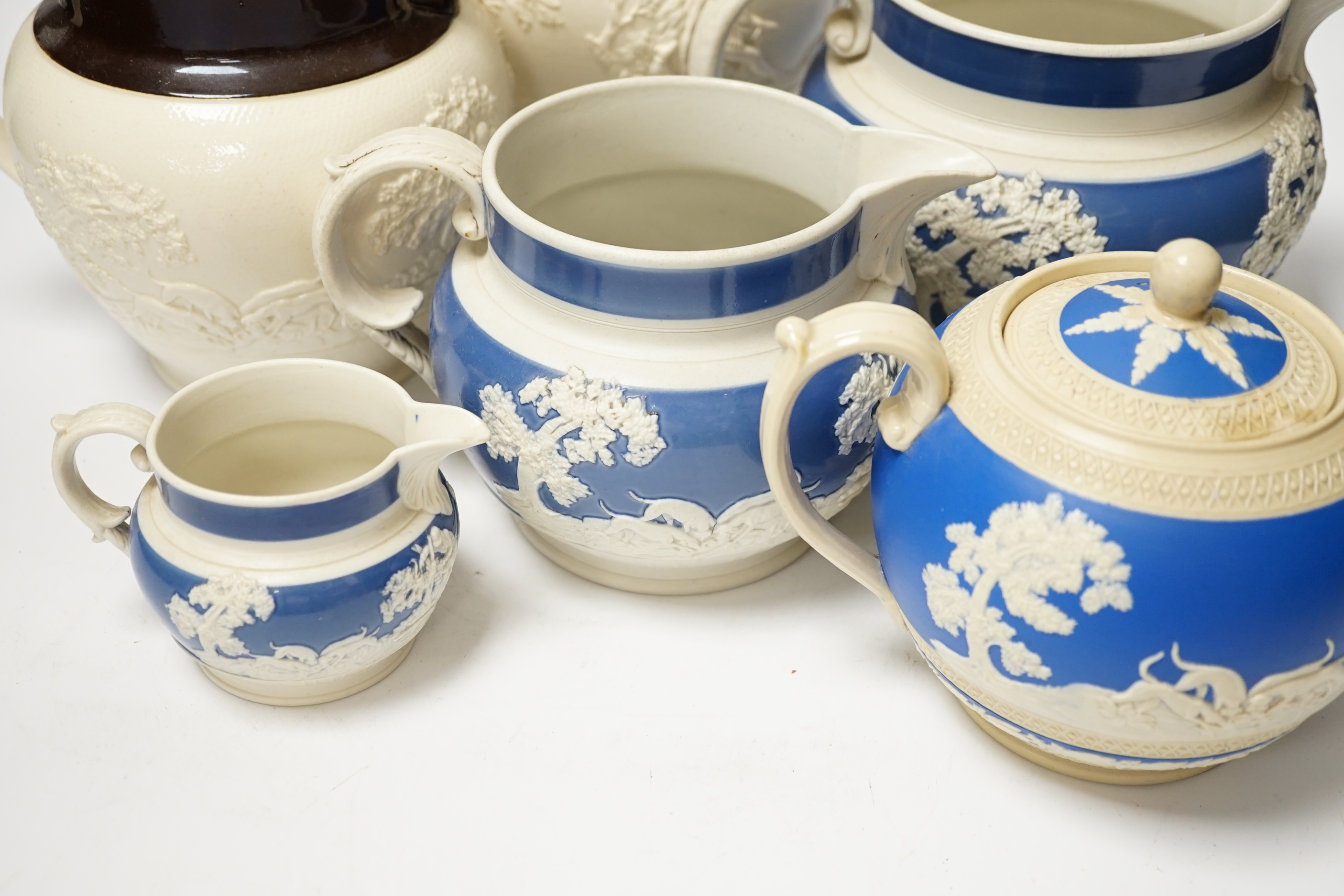 A group of Staffordshire white stonewares: five jugs and a teapot, including Adams, tallest jug 21cm high